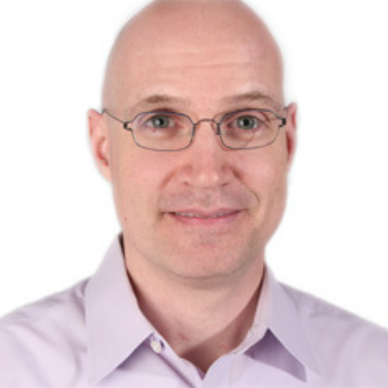 Bald man with glasses wearing a light purple, collared shirt, smiling slightly against a solid white background. Bald man with glasses wearing a light purple, collared shirt, smiling slightly against a solid white background.