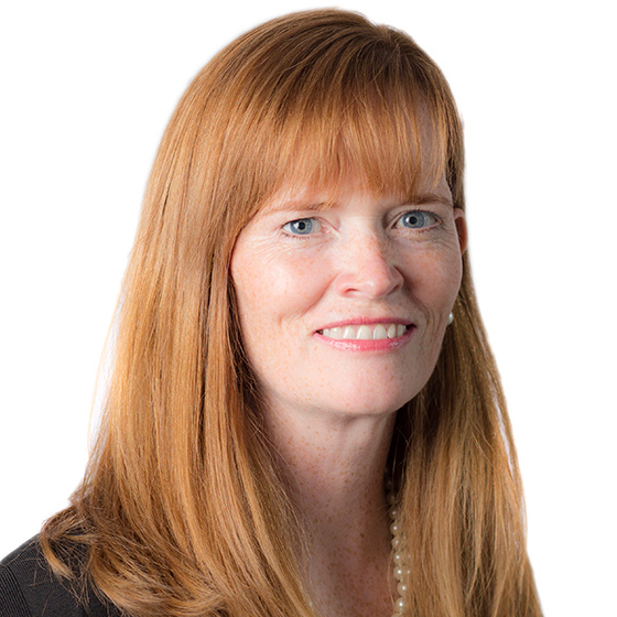 Smiling woman with long, red hair and bangs, wearing a black top and pearl necklace, against a solid white background. Smiling woman with long, red hair and bangs, wearing a black top and pearl necklace, against a solid white background.