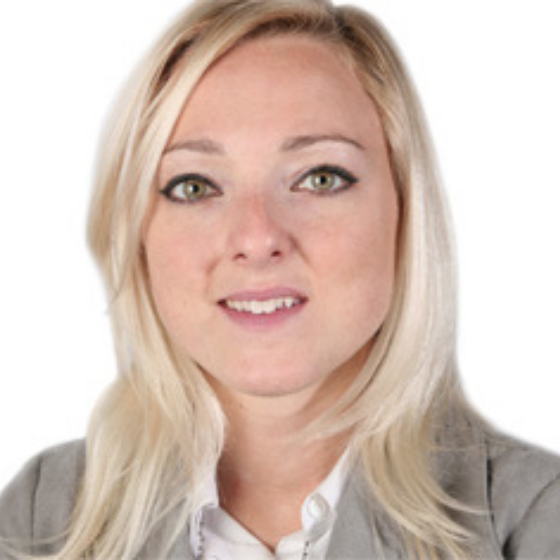 Woman with mid-length blonde hair, wearing a light gray blazer and white shirt, smiling slightly against a solid white background. Woman with mid-length blonde hair, wearing a light gray blazer and white shirt, smiling slightly against a solid white background.