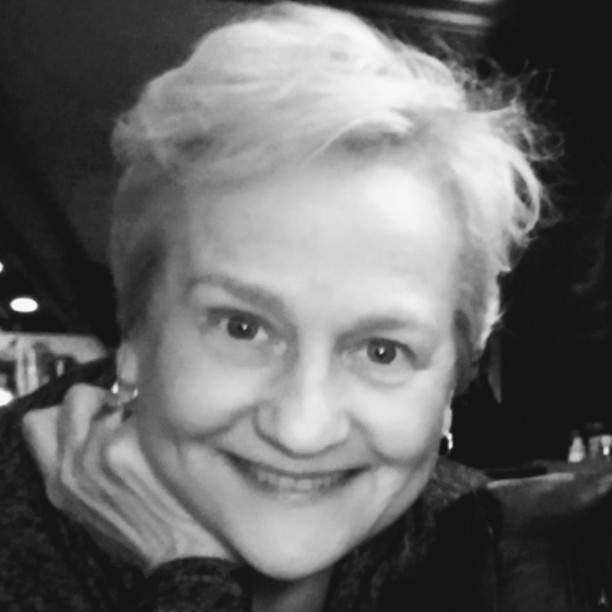 Monochrome picture of a smiling woman with short white hair, against a dark background. Monochrome picture of a smiling woman with short white hair, against a dark background.