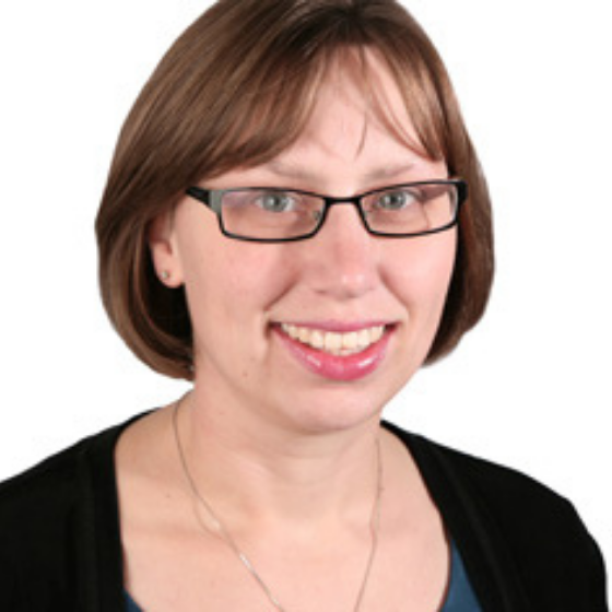 Smiling woman with rectangular glasses and a short bob, wearing a necklace and a black top, against a solid white background. Smiling woman with rectangular glasses and a short bob, wearing a necklace and a black top, against a solid white background.