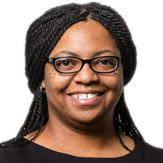 Smiling woman with her long dark brown hair in braids, wearing glasses and a black top, against a solid white background. Smiling woman with her long dark brown hair in braids, wearing glasses and a black top, against a solid white background.