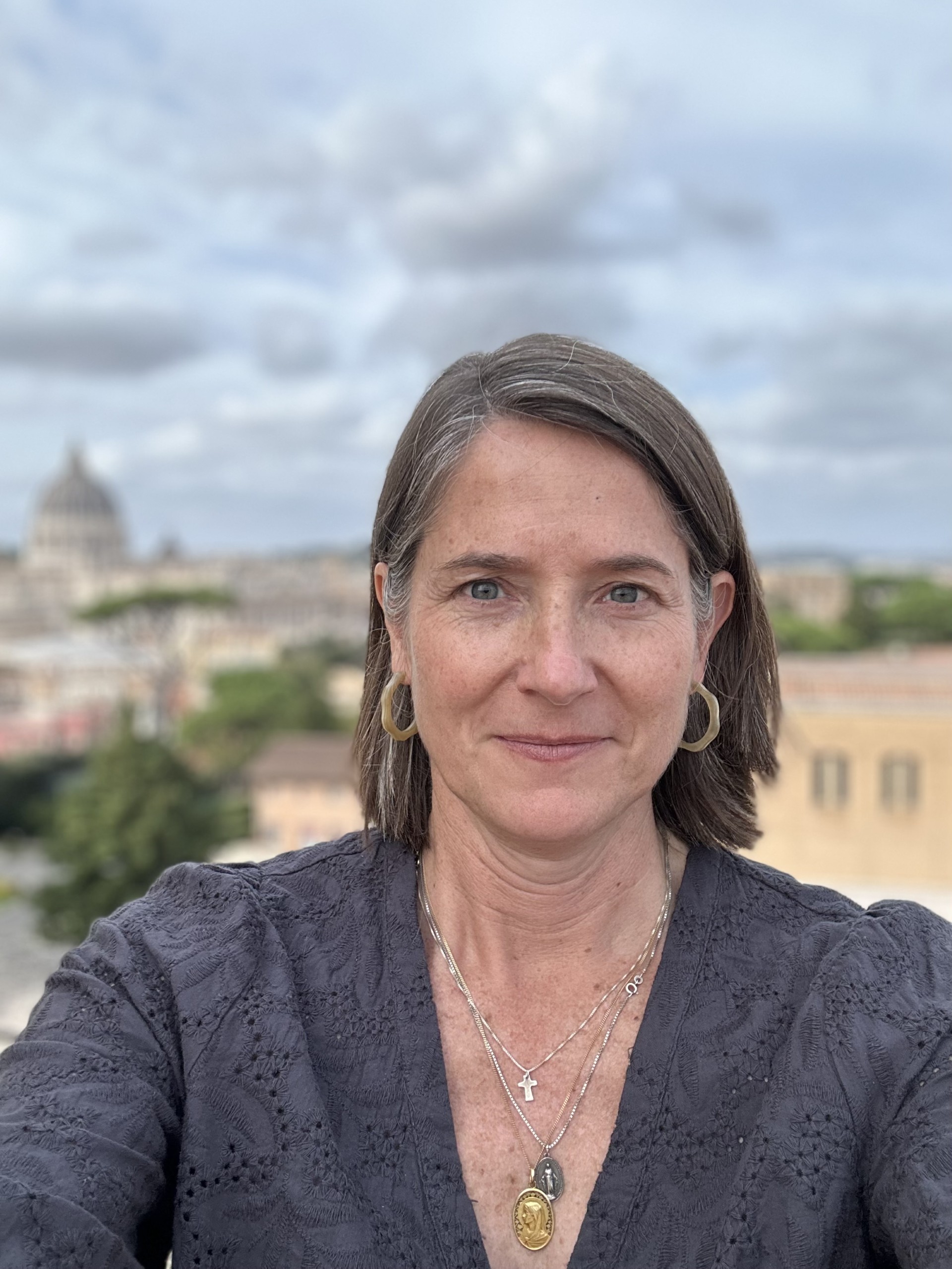 Woman outdoors in Rome with St. Peter’s Basilica visible behind her under a cloudy sky Woman outdoors in Rome with St. Peter’s Basilica visible behind her under a cloudy sky