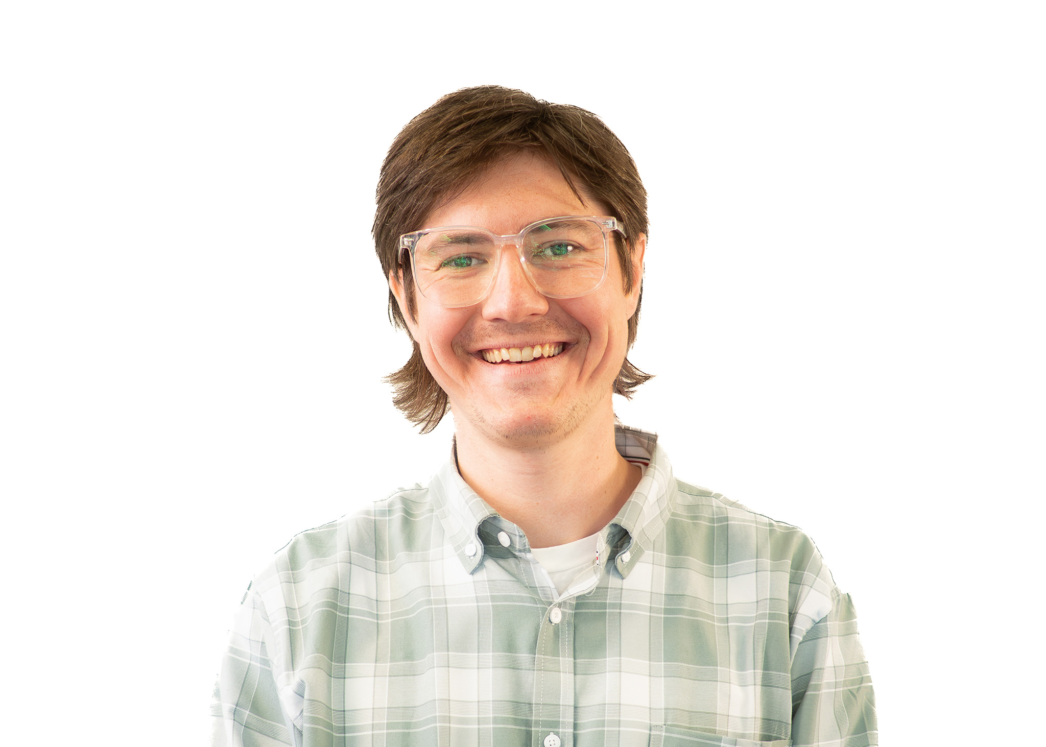 Headshot of a person with short hair and clear-framed glasses smiling, wearing a plaid shirt against a light background Headshot of a person with short hair and clear-framed glasses smiling, wearing a plaid shirt against a light background