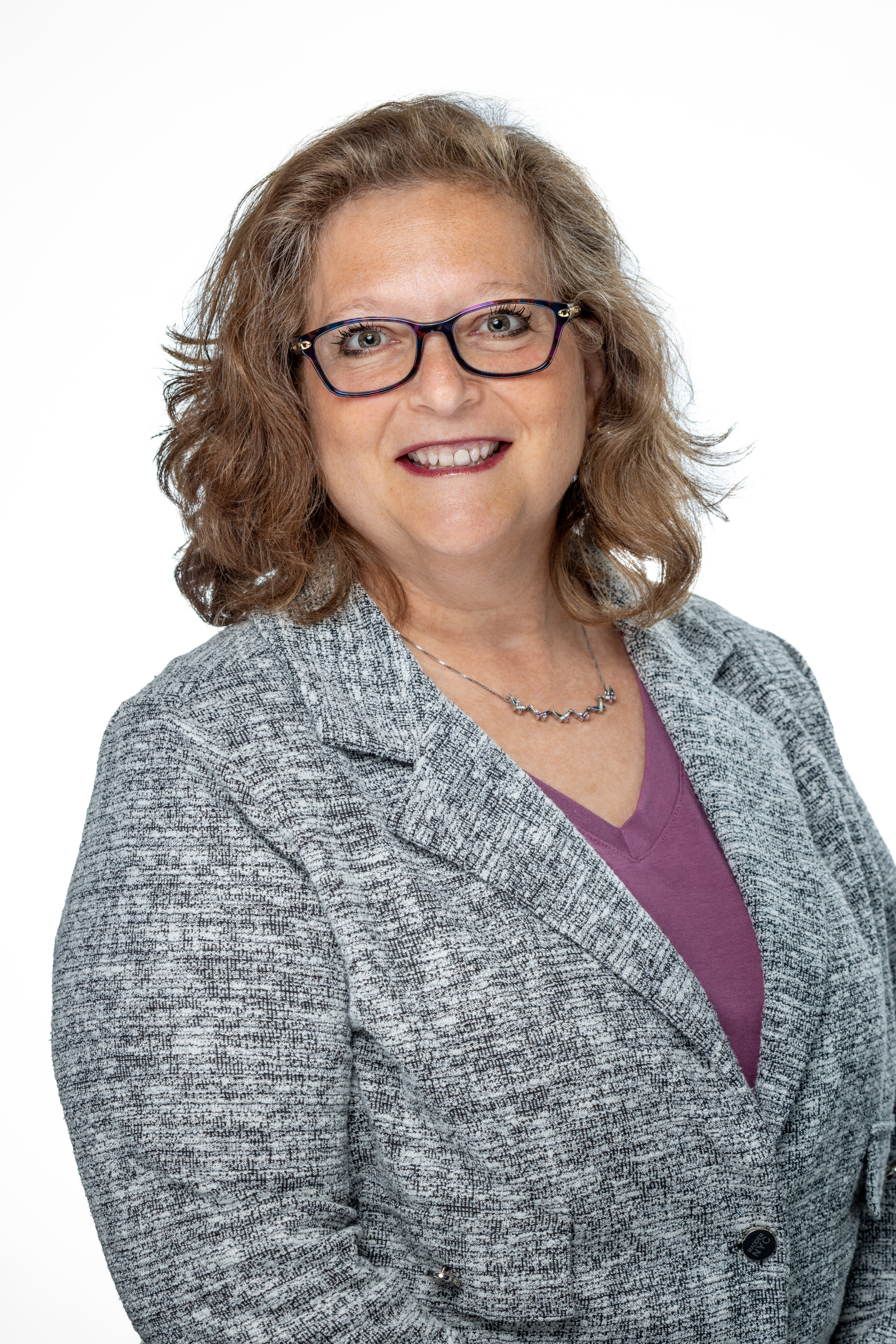Portrait of Amy Greenberg, LCSW, MA.Ed, Assistant Dean for Student Affairs, smiling and wearing glasses, a gray blazer, and a purple top against a light background. Portrait of Amy Greenberg, LCSW, MA.Ed, Assistant Dean for Student Affairs, smiling and wearing glasses, a gray blazer, and a purple top against a light background.