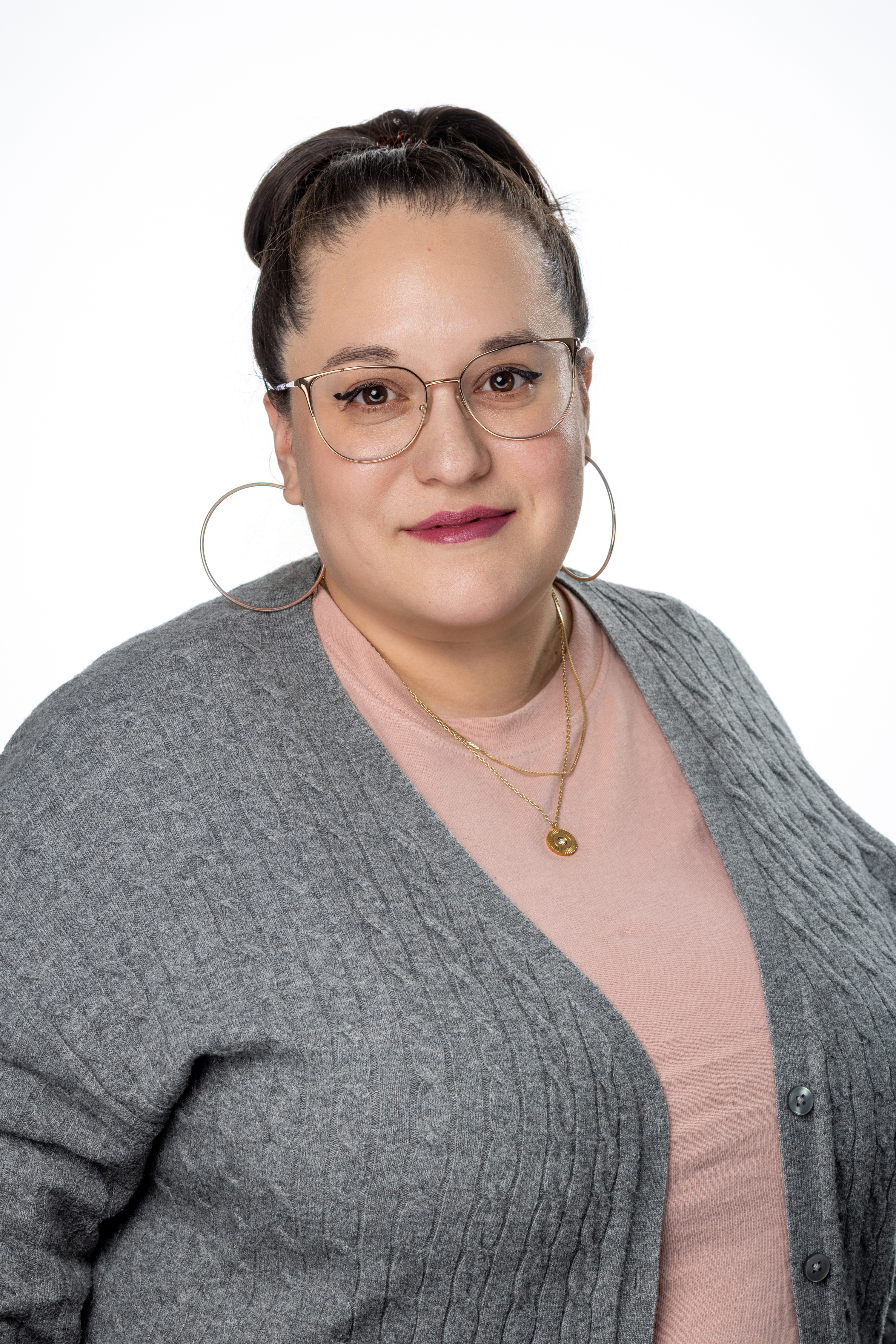 Gabriela Guardiola, Office Coordinator for Academic Affairs, wearing glasses, a pink top, and a gray cardigan, smiling against a light background. Gabriela Guardiola, Office Coordinator for Academic Affairs, wearing glasses, a pink top, and a gray cardigan, smiling against a light background.
