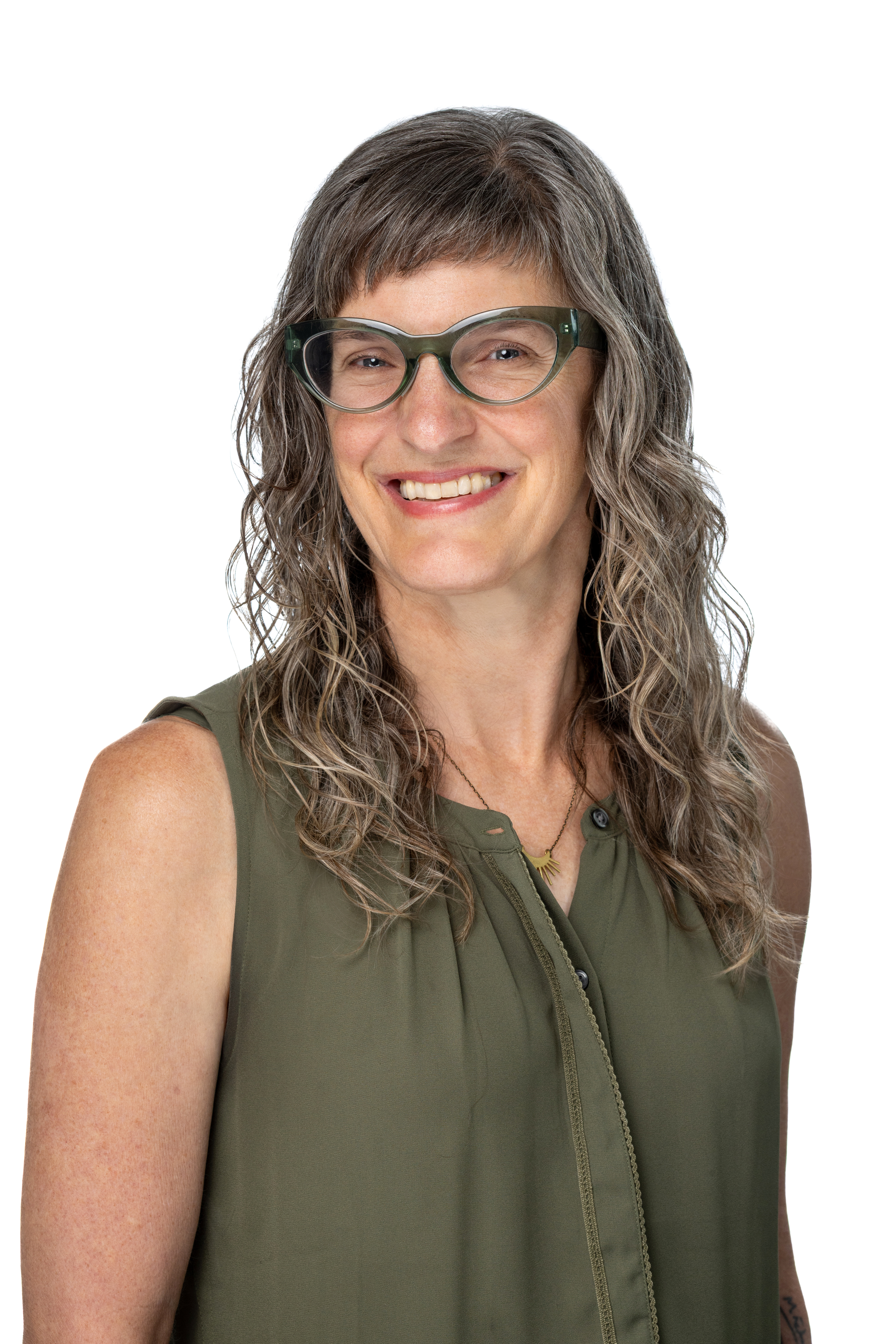 Kate Phillippo, PhD, LCSW, wearing green-framed glasses and a sleeveless olive blouse, smiling against a light gray background. Kate Phillippo, PhD, LCSW, wearing green-framed glasses and a sleeveless olive blouse, smiling against a light gray background.