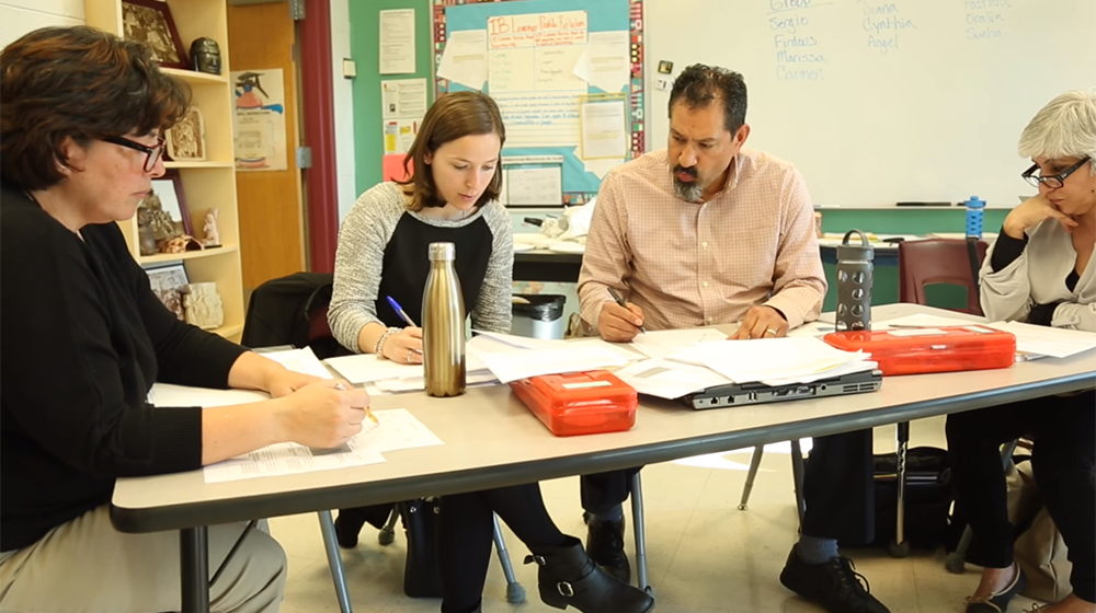 Four educators working at a Chicago Public School classroom table, working on papers, through Loyola's Center for Science and Math Education. Four educators working at a Chicago Public School classroom table, working on papers, through Loyola's Center for Science and Math Education.