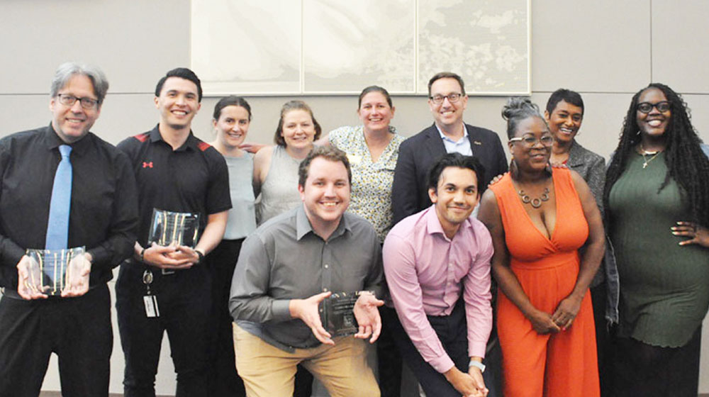 Staff members with their awards gather for a photo with President Mark C. Reed. ITS staff member, Nick Jones, on the far left with his award.