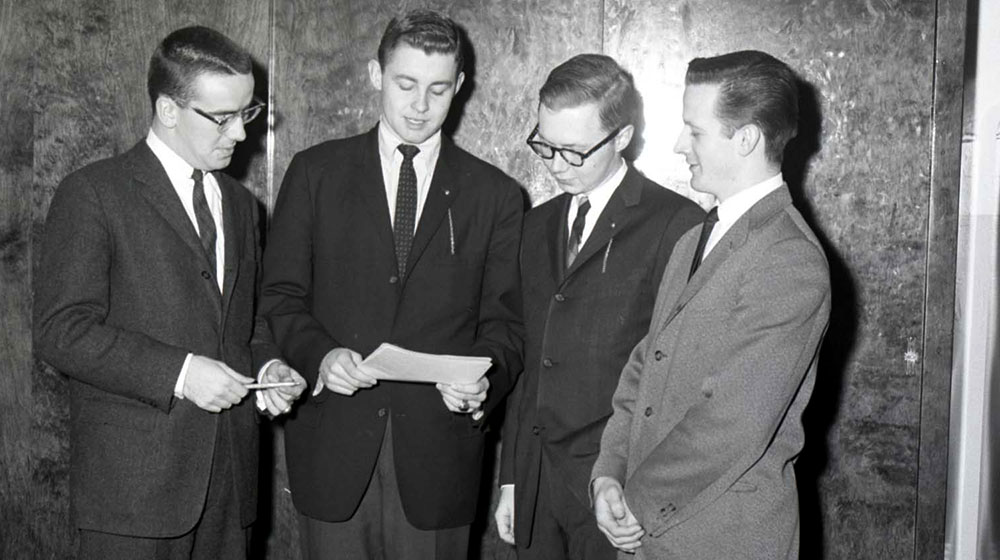 Bill Plante reads a document while surrounded by his Loyola Union colleagues.