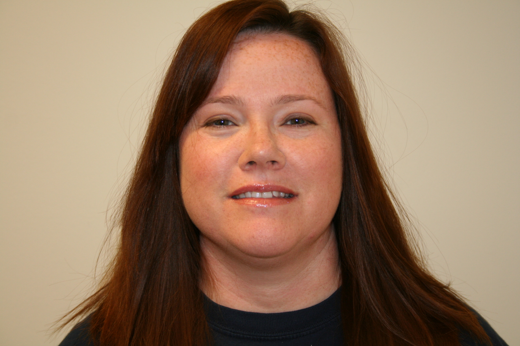 Headshot of a brunette person against a cream background