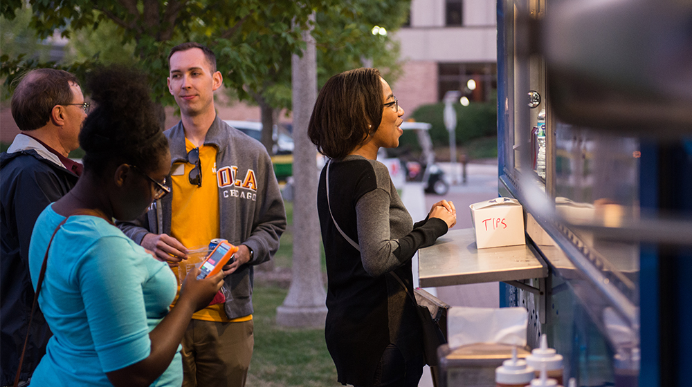 Faculty and staff ordering at a food truck at a Loyola event.