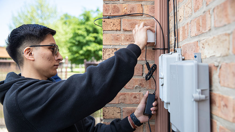 A Loyola University Chicago School of Sustainability student checks a reading on a home in a Chicago area neighborhood.
