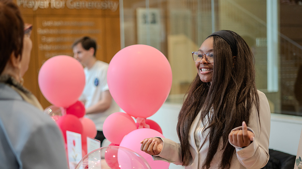 A quinlan student smiles in front of pink balloons from her business poster A quinlan student smiles in front of pink balloons from her business poster