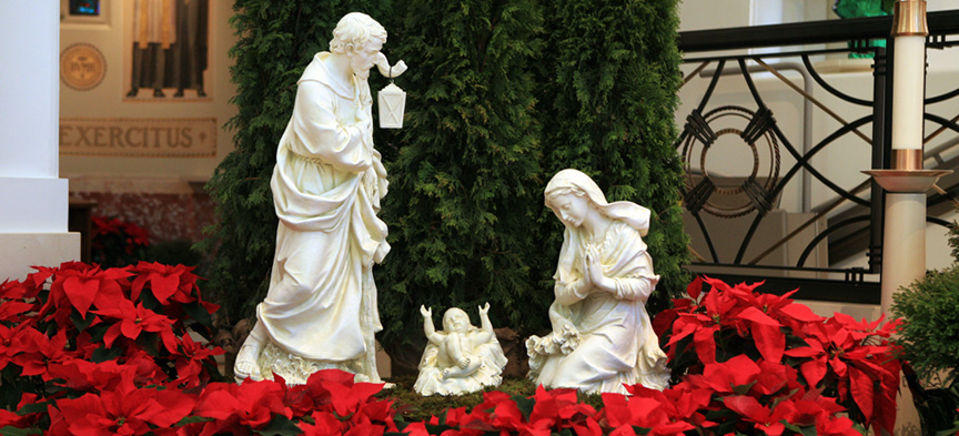 Manger scene with Jospeh, Mary and Jesus amidst red poinsettias