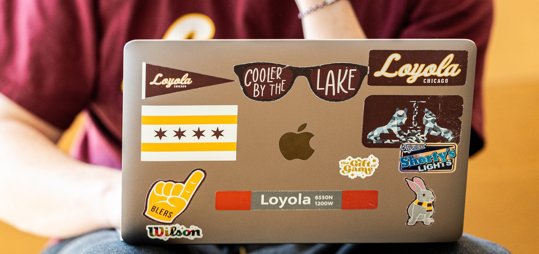 SCPS Loyola student at laptop with Loyola stickers
