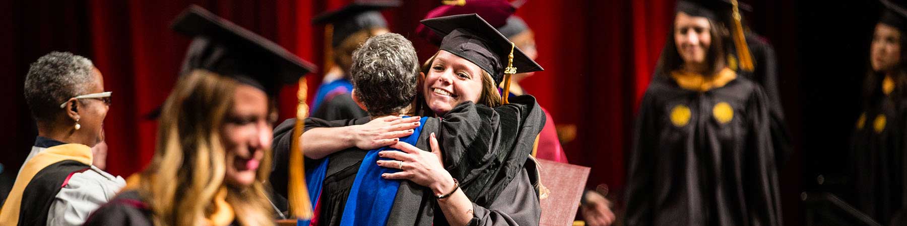 Student hugging faculty member at graduation