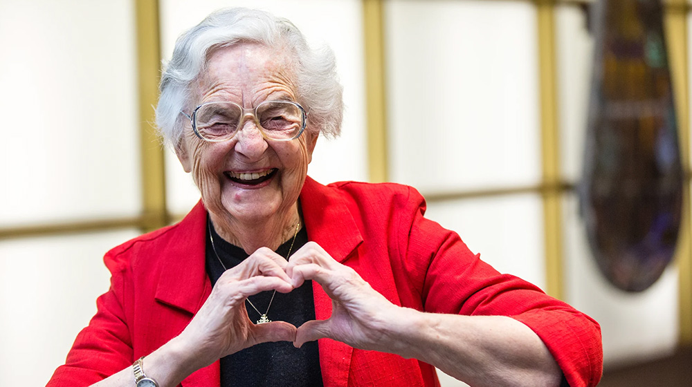 Sister Jean laughing and making the heart symbol with her hands Sister Jean laughing and making the heart symbol with her hands
